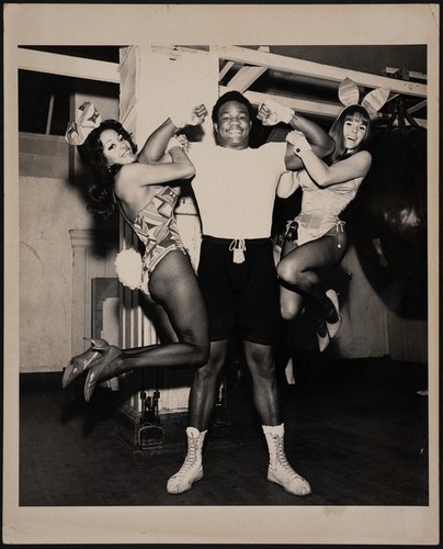 George Foreman lifting Playboy Bunnies Nikki Johnson and Wendy Abbott during a break in his training