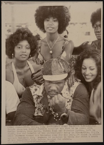 George Foreman displays his fist as he poses with four women at his Pleasanton, California training camp