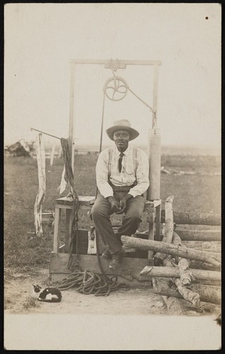 African American man sitting on a mine shaft opening