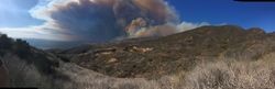 Smoke billows over hills