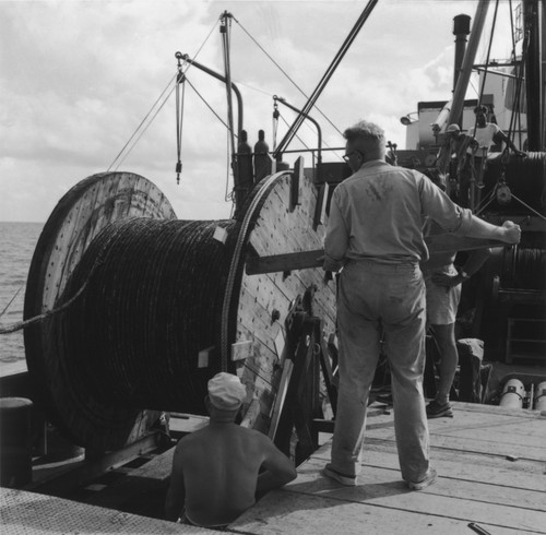 John D. Isaacs (right front) and unidentified men unwind cable