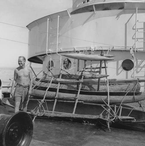 Russell W. Raitt stands by outrigger canoe on deck of R/V Horizon, while Helen Raitt looks out from porthole