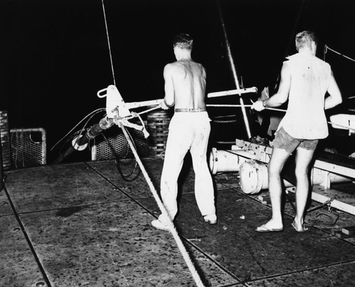 Core oceanographic instrument lowered into the ocean at night