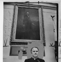 The Rev. Father Leo McAllister, California Assembly chaplain, standing under a portrait of President Lincoln