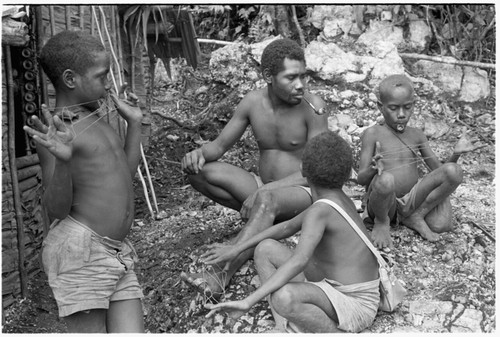Laete'eboo and his sons playing with lalefui'olanga string figures in front of the men's house