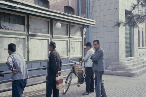 Pedestrians reading newspapers on the street (1 of 2)