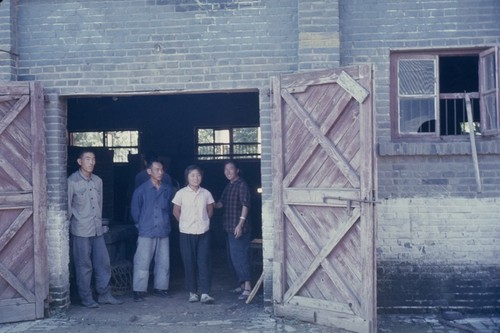 Workers standing at entrance to brick building