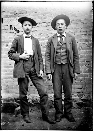 Two Chinese men posing in front of a building, wearing western suits