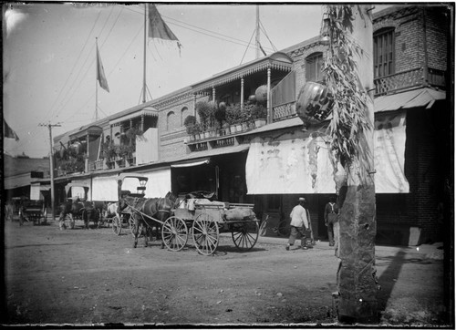 Street view of horse-drawn carts and building with balconies