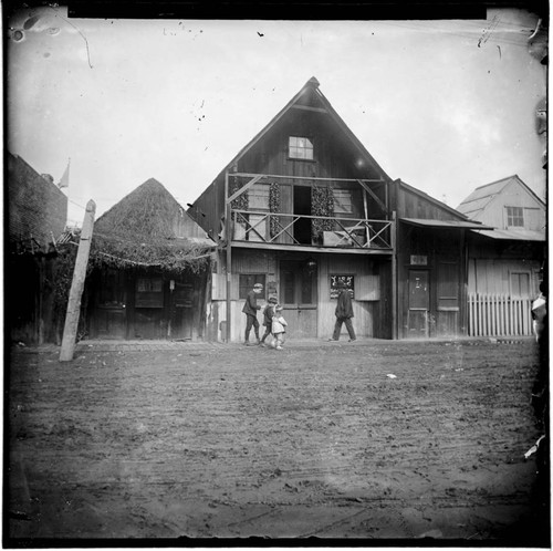 Adults and children walking by wooden buildings