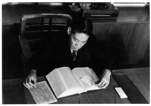 Y. C. Hong reading a book at his desk