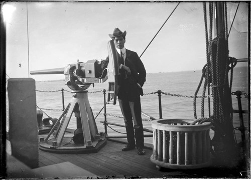 Man posed on a naval vessel, leaning on a gun