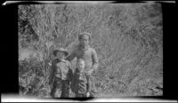 Ambrose Cline, H. H. West, Jr. and Keyo posing in front of tall brush, San Francisquito Canyon, about 1923