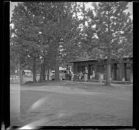 Distant view of Maud West, Agnes Whitaker and Mertie West sitting outside their cabin at Knight's Camp, Big Bear Lake, 1944