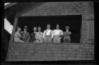 Worm's-eye view group portrait of members of the West, Whitaker, Shaw, Prickett and Witherby families standing on a porch, Manhattan Beach, about 1930