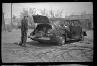 W. W. Witherby stands near the trunk of his car while stopping for lunch, Olancha, 1947