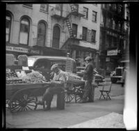 Street venders sell produce from carts sitting along a street in Chinatown, New York, 1947