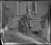 H. H. West poses next to the West's house while Wayne West reaches toward him, Los Angeles, about 1900