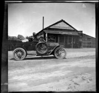 Al Schmitz poses in his car in front of the Elizabeth Lake Hotel & Restaurant, Lancaster vicinity, about 1915