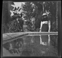 Louise Ambrose, Charles Rucher and Nella West stand near a fountain at Bailey's Ranch, Arcadia, 1899