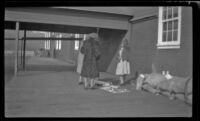 Women browse the souvenirs a Native American woman has for sale, Sitka, 1946