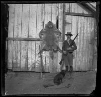 Ed Smith posing with a rifle, dog and a coyote pelt, Pomona, about 1895