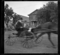 H. H. Cooper drives by the West's house in a horse-drawn carriage, Los Angeles, (circa 1901?)