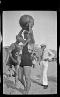 Salesman Burt holds a beach ball above his head, Hermosa Beach, about 1932