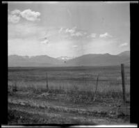 Field and fence with a mountain range (possibly including Mount Lassen) in the distance, Burney vicinity, 1915