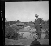 H. H. West stands holding a cigar by the Nishnabotna River, Red Oak, 1900