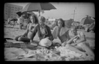 Margaret Deming, Mertie West, Jane Deming and H. H. West, Jr. lounge on the beach, Hermosa Beach, 1937