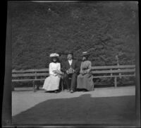 Three unknown persons sitting on a park bench, San Jose, about 1900