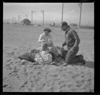 Elizabeth West and Maude Hamilton lay in the sand while Frances West sits up and Mary West and Guy West kneel beside them, Venice, about 1908