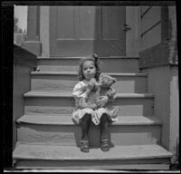 Elizabeth West sits on the back steps of a house holding teddy bear, Los Angeles, about 1907