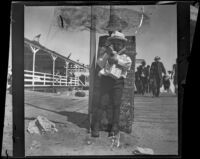 Lester Shaw stands on the boardwalk holding firecrackers, Santa Monica, 1901