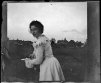 Ellen Lorene (Pinkie) Lemberger stands outside holding a plate, Ottumwa, 1900