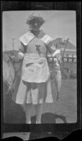 Frances West stands in the West's backyard holding fish, Los Angeles, about 1919