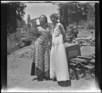 Frances West Wells and Mertie Whitaker West stand in front of a woodpile outside a cabin, Big Bear, 1932