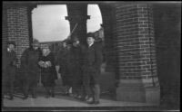 Attendees of the Automotive Accessories Jobbers Convention and their wives stand under a brick arcade, New York, 1917