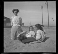 Mary West kneels in the sand while Elizabeth and Frances West sit next to her and Maude Hamilton reclines in between, Venice, about 1908