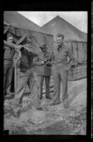 Jose Miller holds a pipe like a baseball bat while fellow servicemen watch (negative), Camp Murray, 1941 or 1942