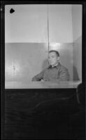 PFC H. H. West, Jr. sits behind a desk while stationed at Dutch Harbor, Dutch Harbor, 1943