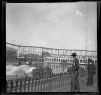 Two men watch the shoot the chutes ride and the Scenic Railway roller coaster, San Francisco, 1900