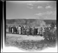 Tour group gathered around a geyser in Upper Geyser Basin and looking towards Old Faithful Inn, Yellowstone National Park, 1942