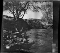 Cleo Swain washing kettles on the bank of Piru Creek, Los Padres National Forest vicinity, about 1917