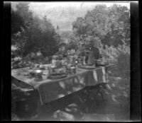 H. H. West Jr. and Forrest Whitaker sit at a table at a campsite, Inyo County vicinity, about 1930