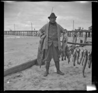 H. H. West posing while holding two of the fish he caught, Newport Beach, 1914