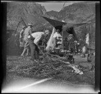 William Shaw chops wood while others gather at their campsite near Rush Creek, Mono County vicinity, 1929