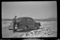 W. W. Witherby poses beside his car on the grade going to Panamint Valley, Death Valley National Park vicinity, 1947