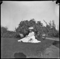 Daisy Conner sits in the grass at Covina city park, Covina, June 1900